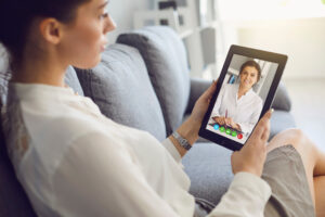 Frau spricht über Videochat mit einer Ärztin zum Thema Pillenrezept online