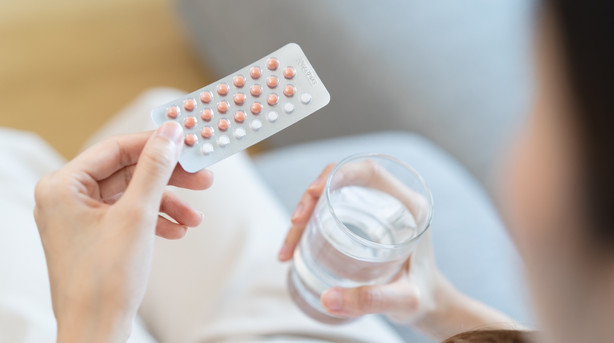 Frau hält Antibabypille und ein Glas Wasser